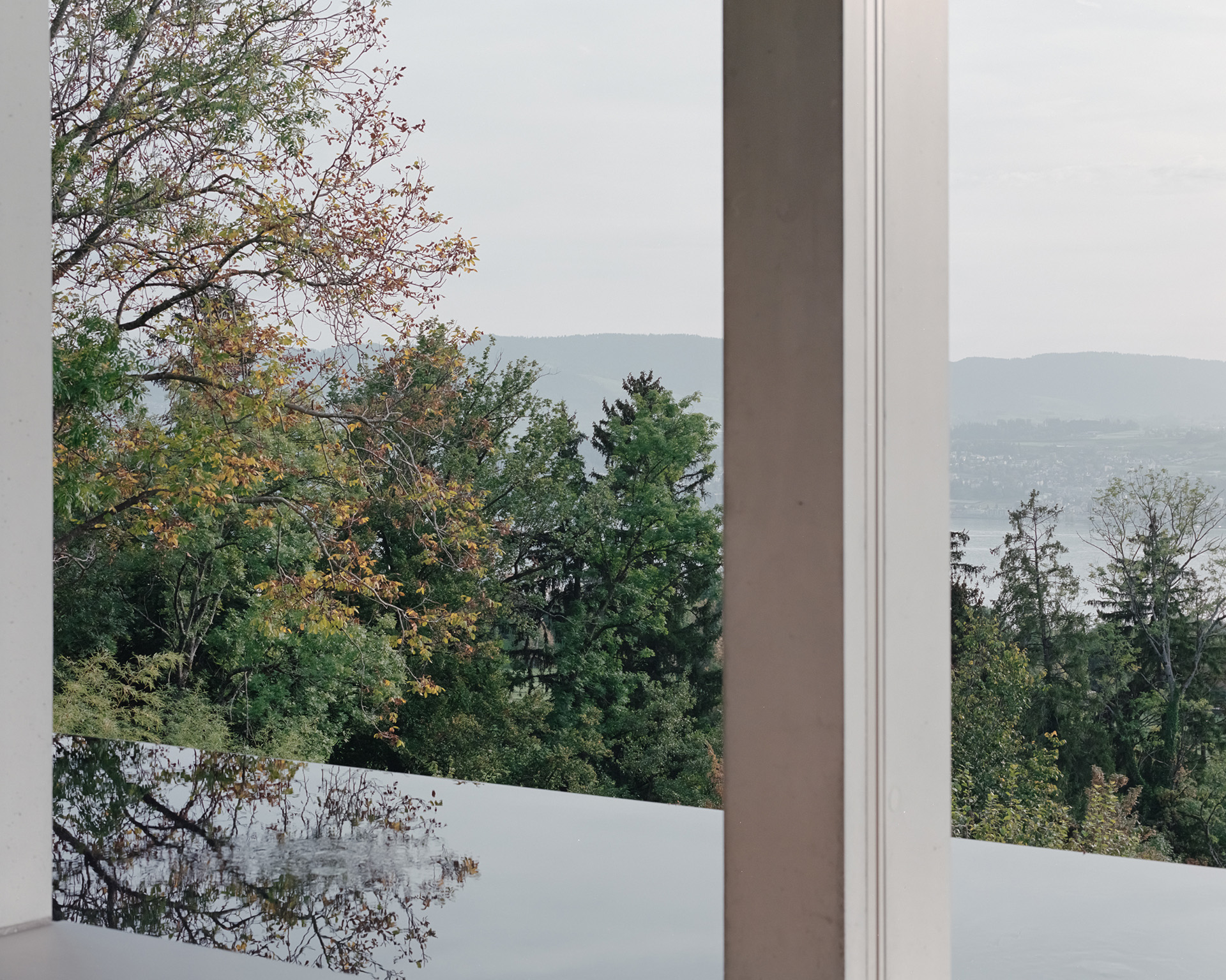 Terraza de muro blanco con vista a árboles y un lago distante.
